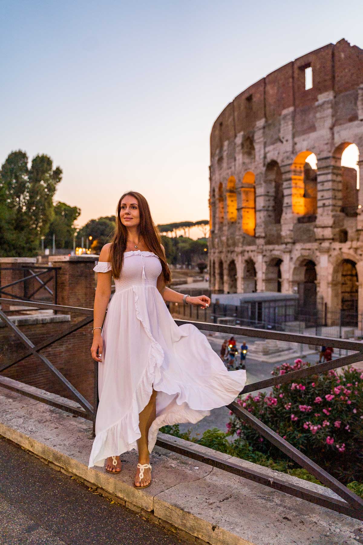 Girl in a white dress in front of the Colosseum at sunset