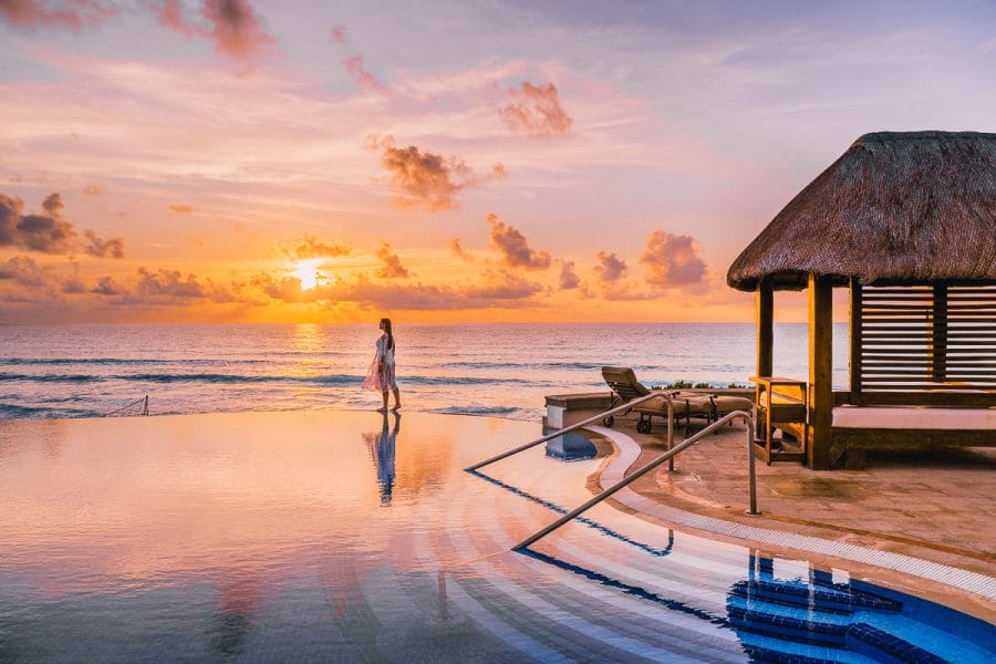 Girl walking on the edge of an infinity pool at sunrise at JW Marriott Cancun