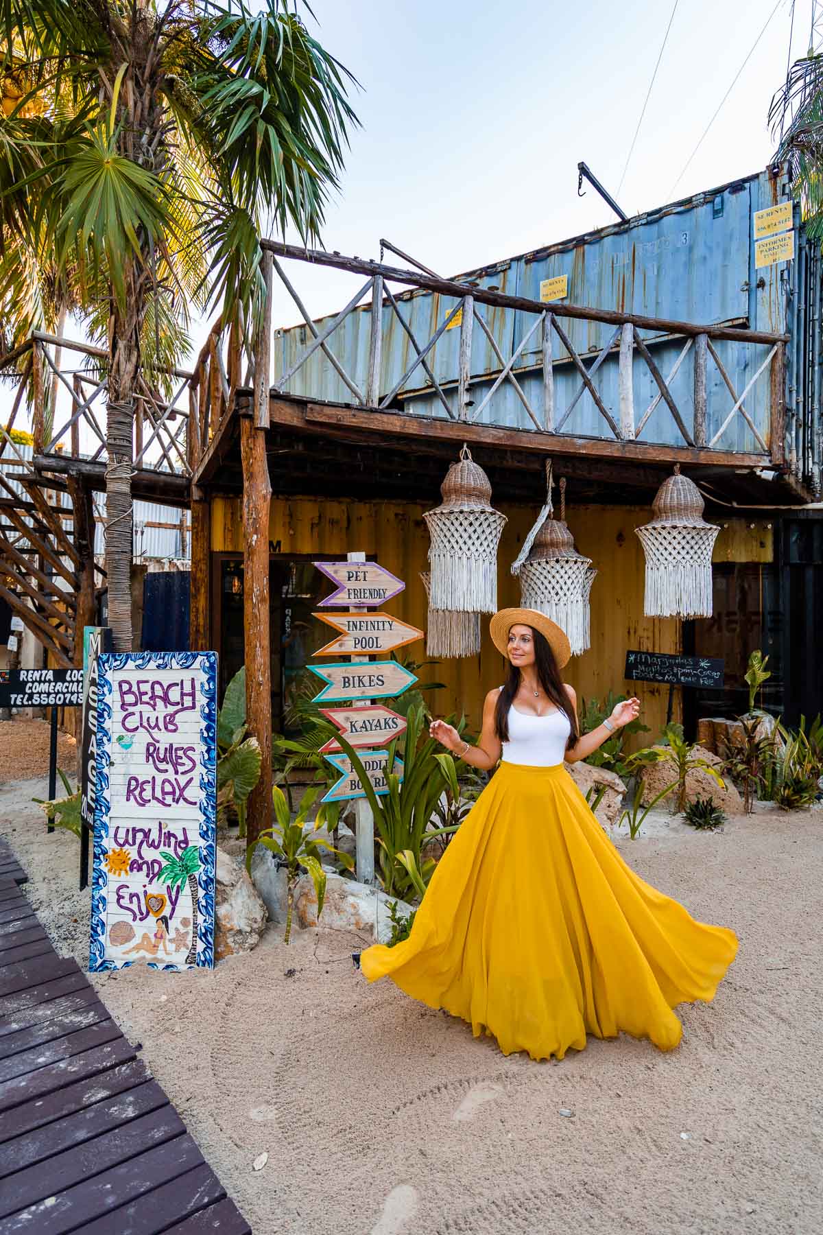 Girl in yellow skirt in front of a Beach Club Sign at Villa Alquimia, Tulum