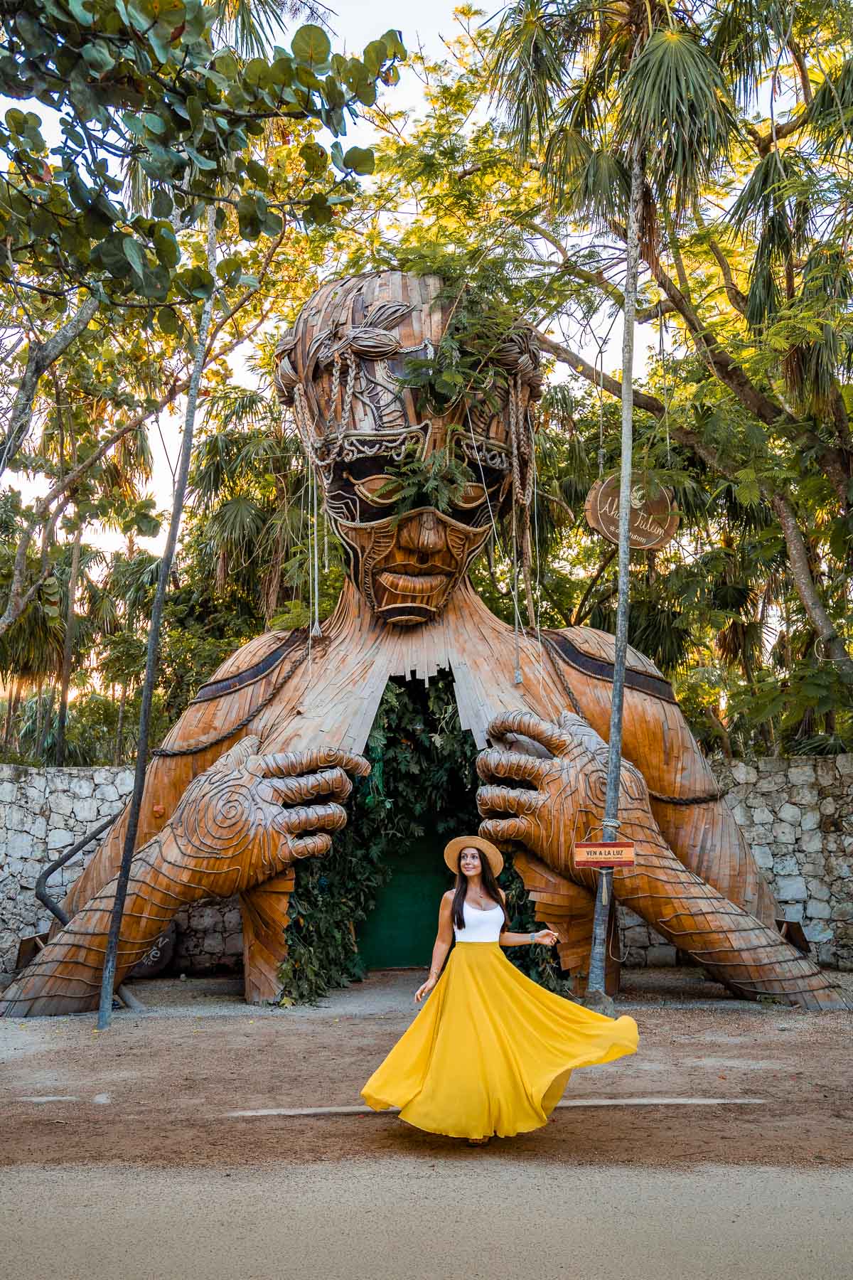Girl in yellow skirt in front of Escultura “Ven a la Luz”, a famous Tulum Instagram spot