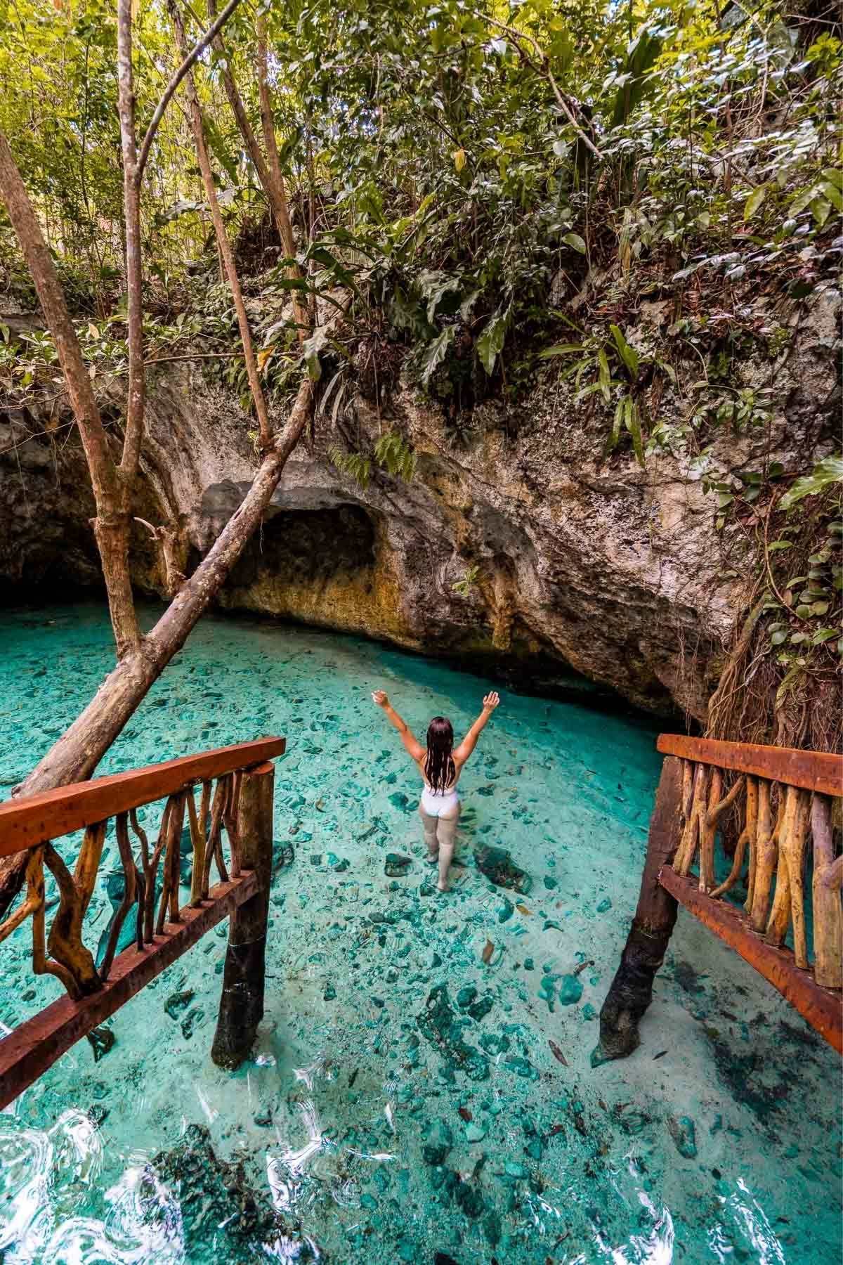 Girl in white swimsuit in the blue waters at Gran Cenote, one of the best Instagram spots in Tulum