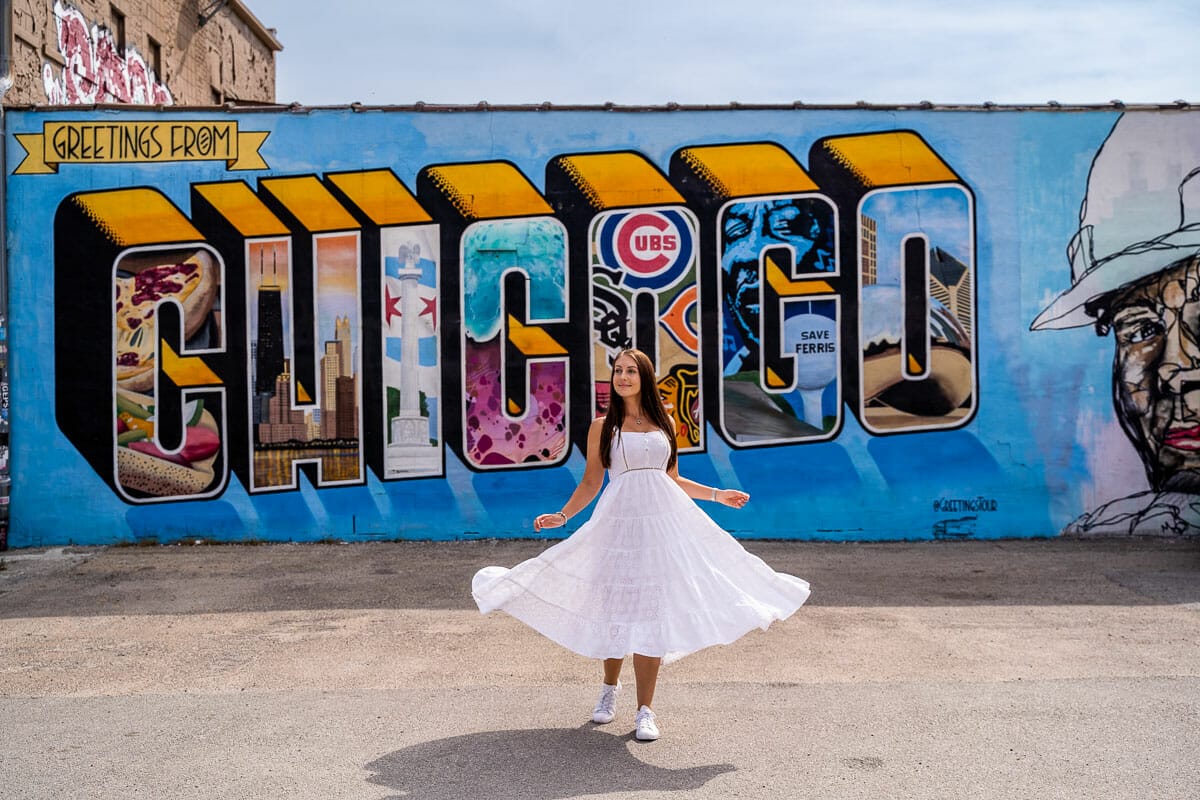 Girl in white dress in front of the Greetings from Chicago Mural