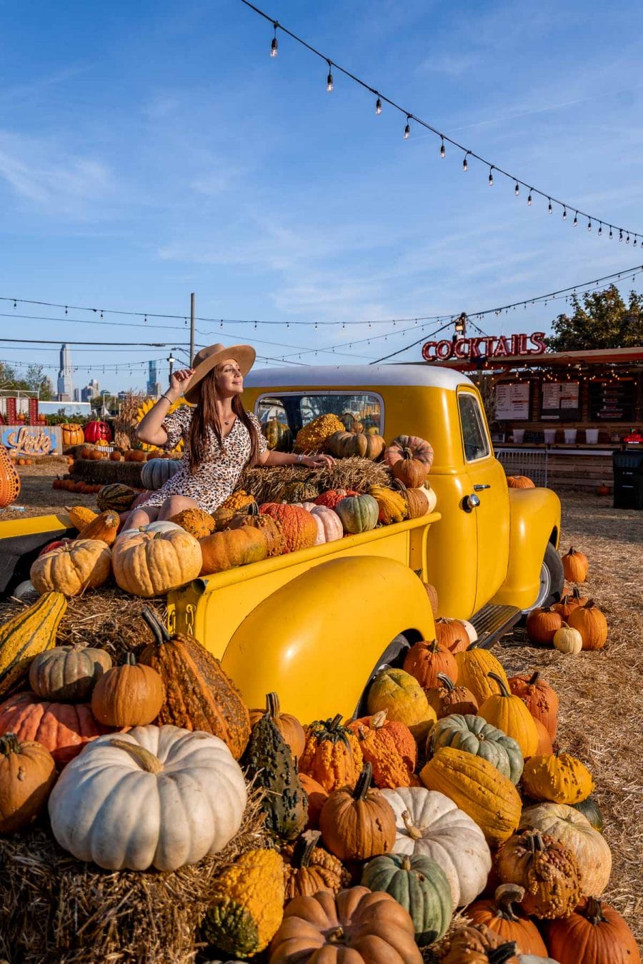 Girl sitting at the back of a yellow car full of pumpkins at Jack's Pumpkin Popup in Chicago