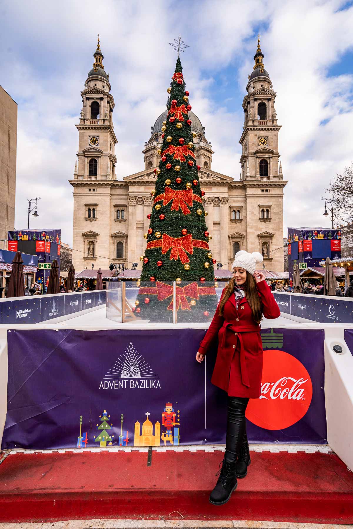 Girl in red coat in front of the Christmas tree at St. Stephen's Basilica, Budapest