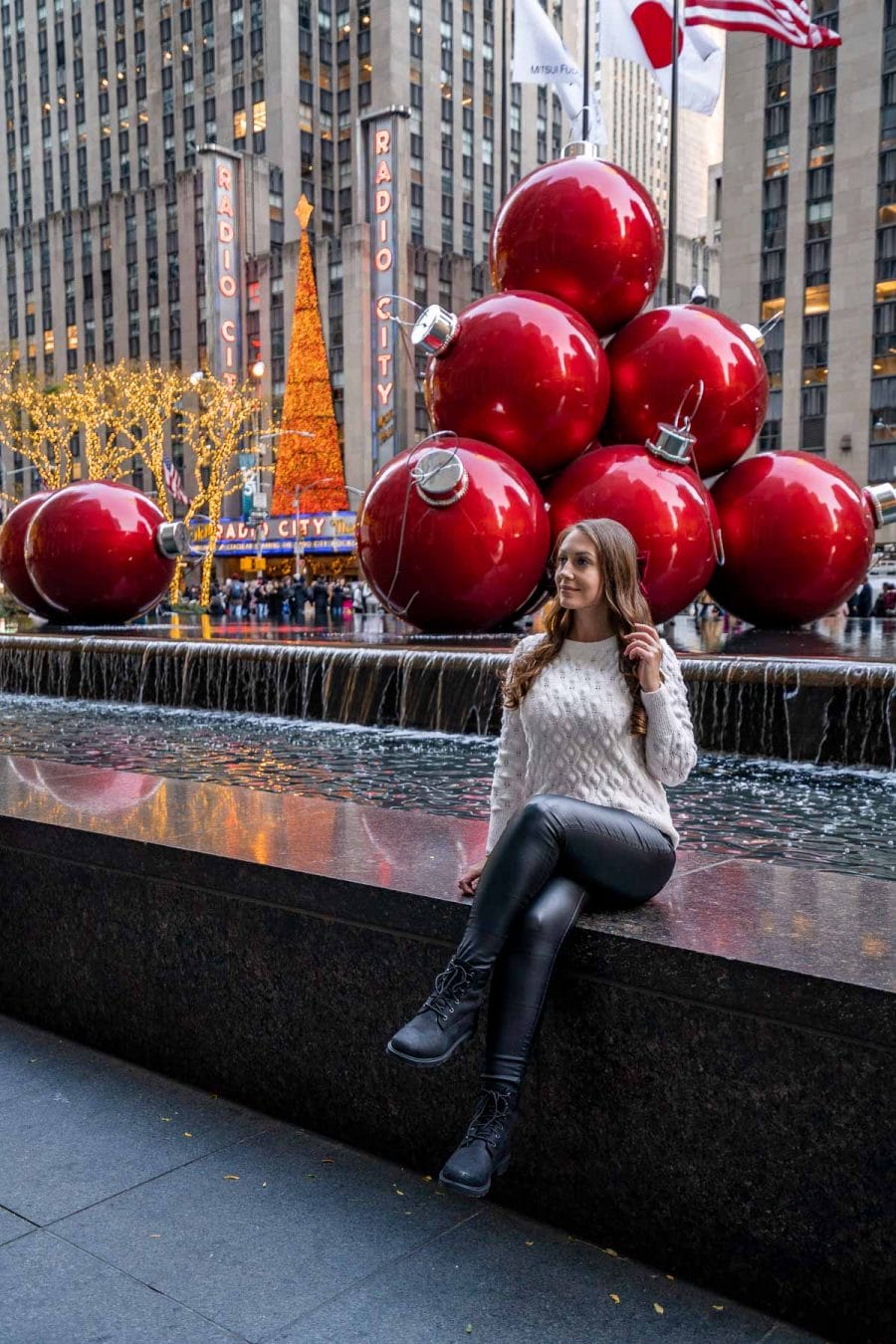 Girl sitting in front of the Christmas Balls Fountain in New York