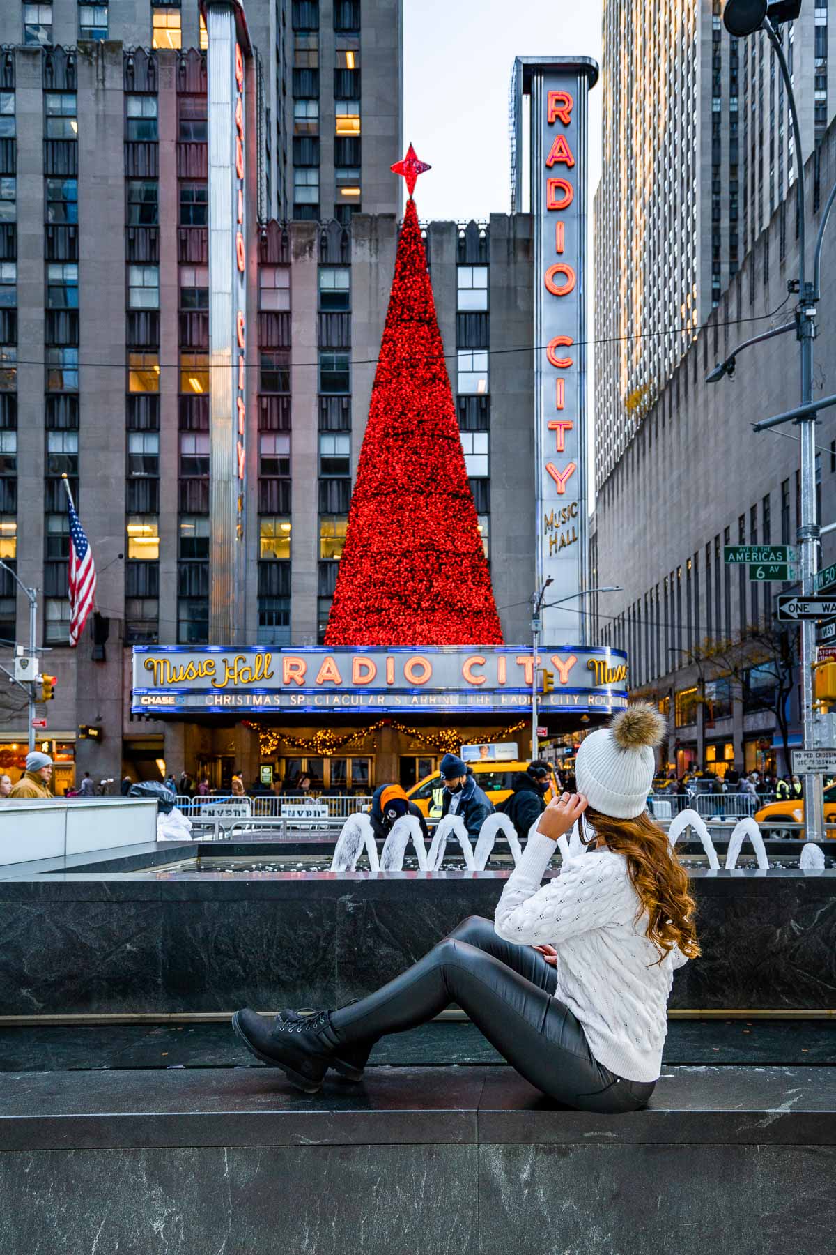 Girl in white sweater in front of the Christmas tree at Radio City Music Hall