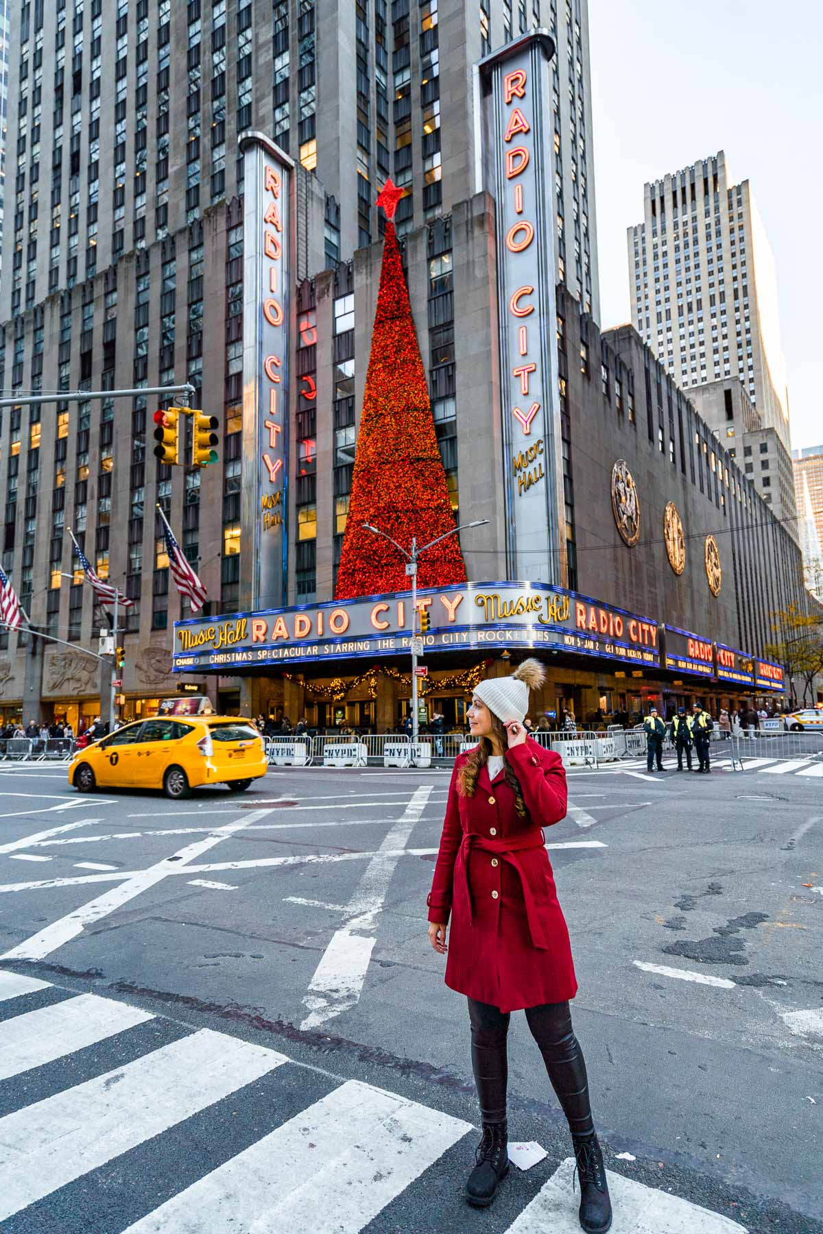 Girl in red coat in front of the Christmas tree at Radio City Music Hall