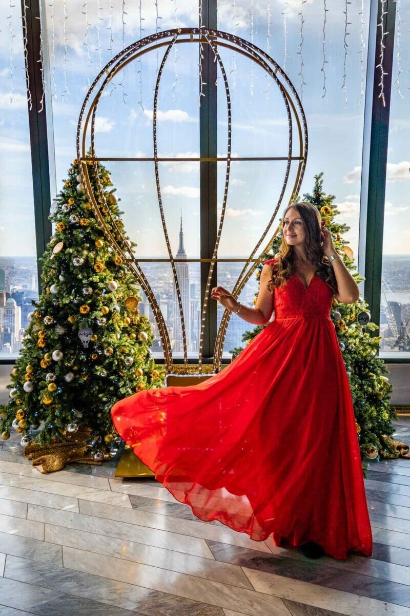 Girl in red dress in front of Christmas trees at the Edge