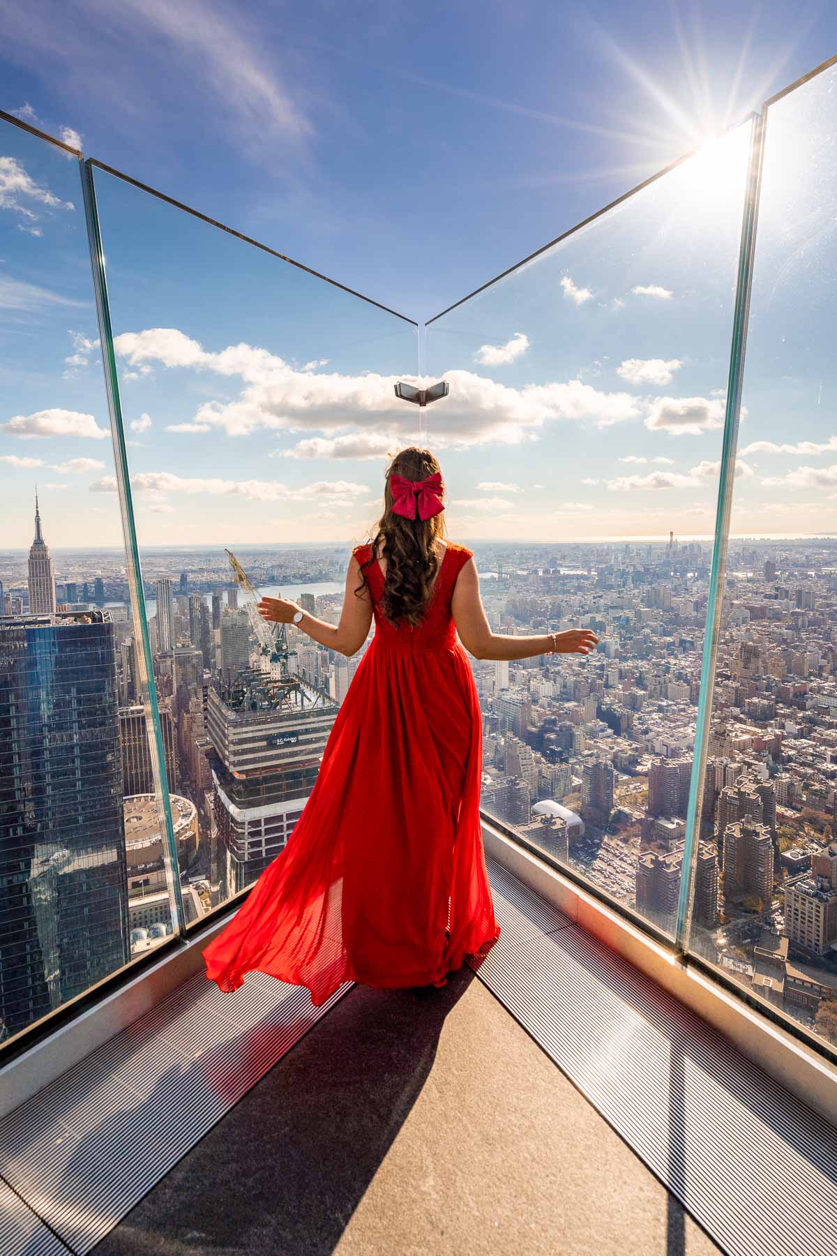 Girl in red dress looking at the New York skyline from the Edge