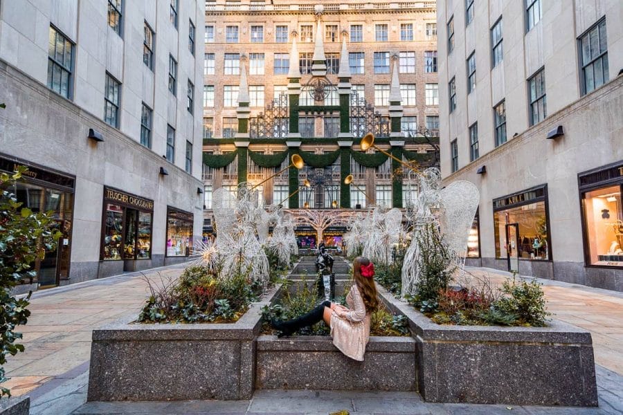 Girl in a sequin dress sitting in the Channel Gardens overlooking Saks Fifth Avenue