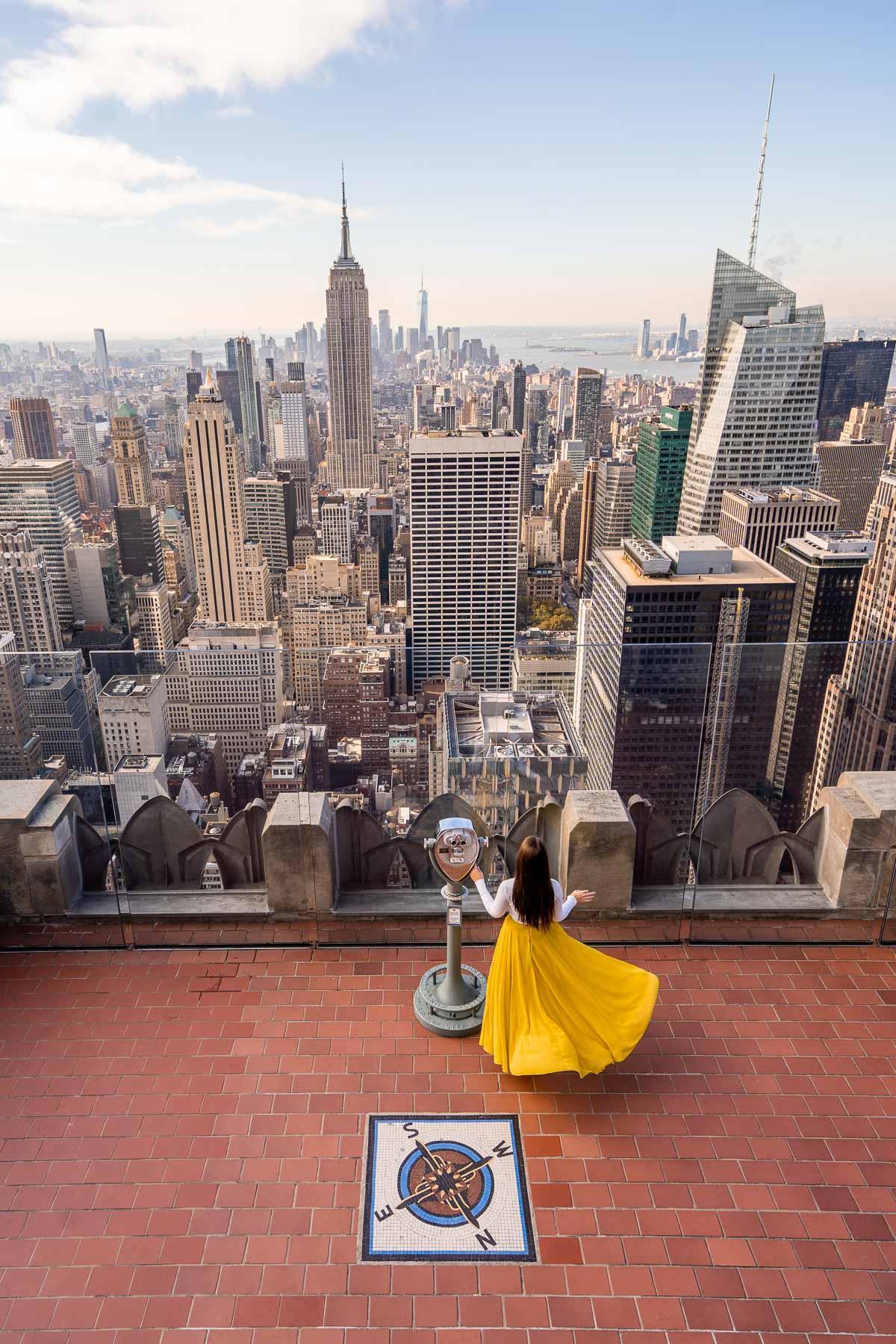 Girl in yellow skirt looking at the Manhattan skyline at Top of the Rock