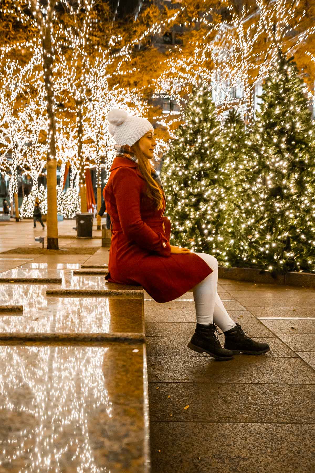 Girl sitting on a bench in Zuccotti Park with Christmas lights in New York
