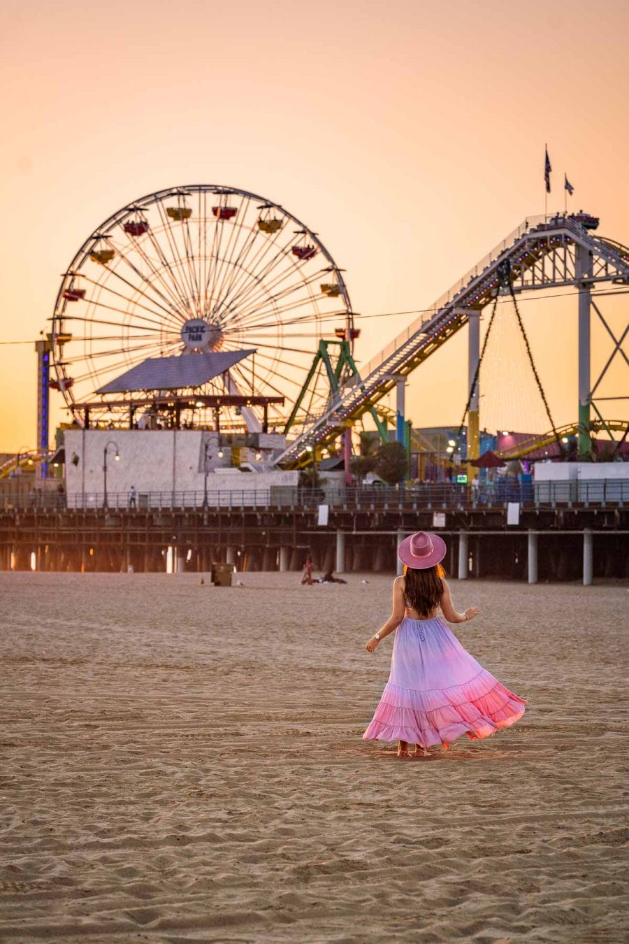 Girl standing on the beach in Santa Monica Pier at sunset
