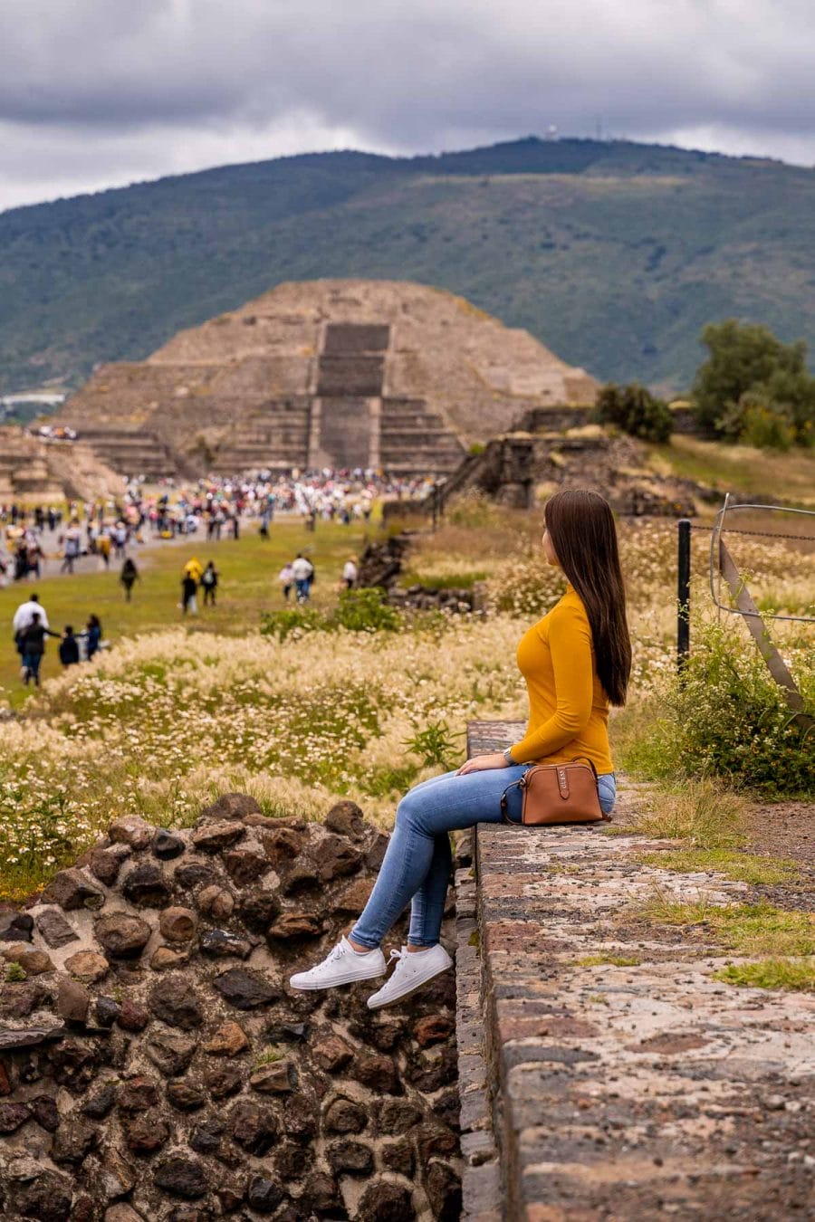 Girl sitting at Teotihuacan, looking at the Temple of the Moon