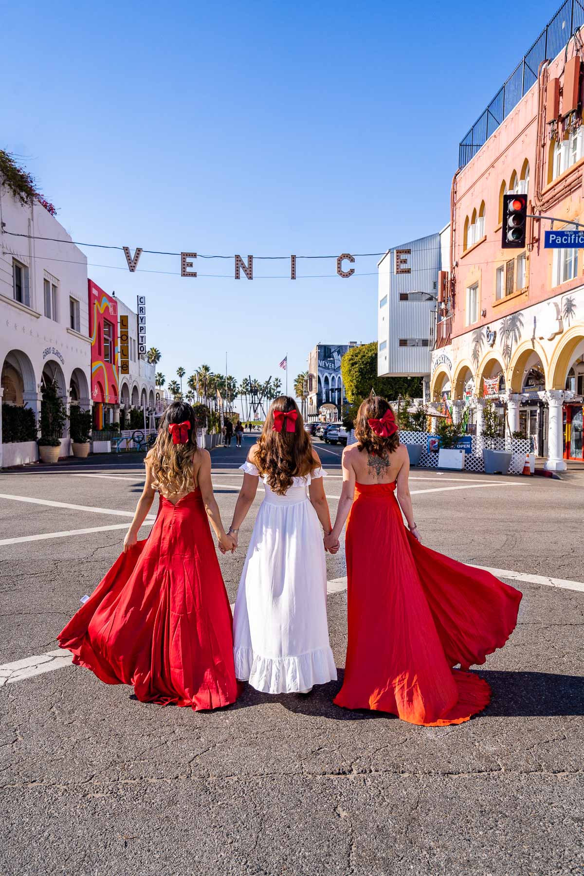 Girls in white and red dresses in front of the Venice Beach Sign, one of the most Instagrammable places in Los Angeles