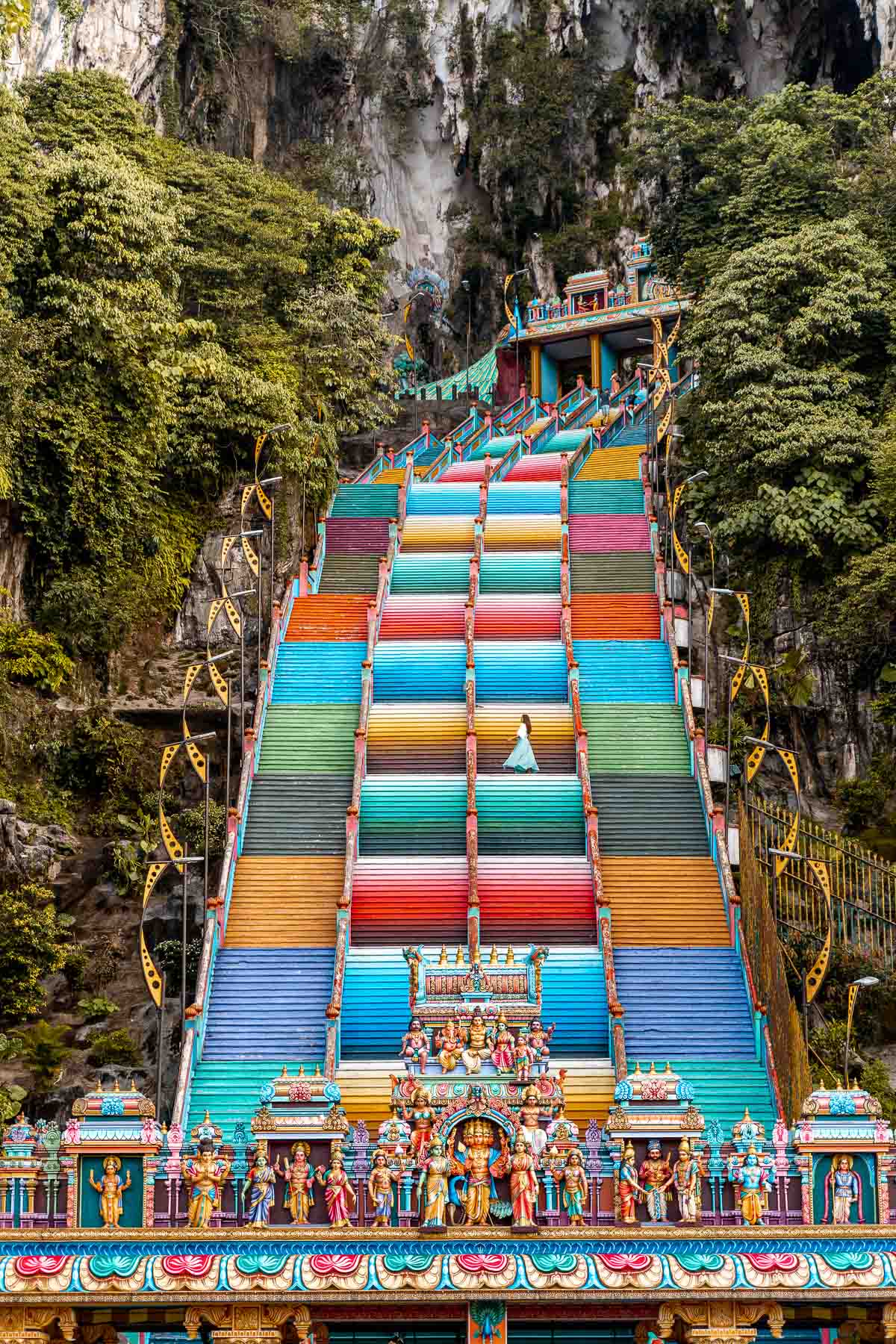 Girl in a blue dress standing on the colorful stairs at Batu Caves, Kuala Lumpur