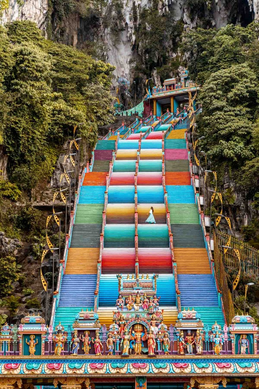 Girl in a blue dress standing on the colorful stairs at Batu Caves, Kuala Lumpur
