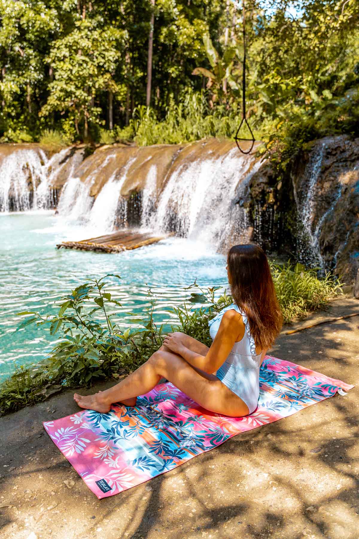 Girl sitting on a beach towel at Cambugahay Falls in Siquijor, Philippines