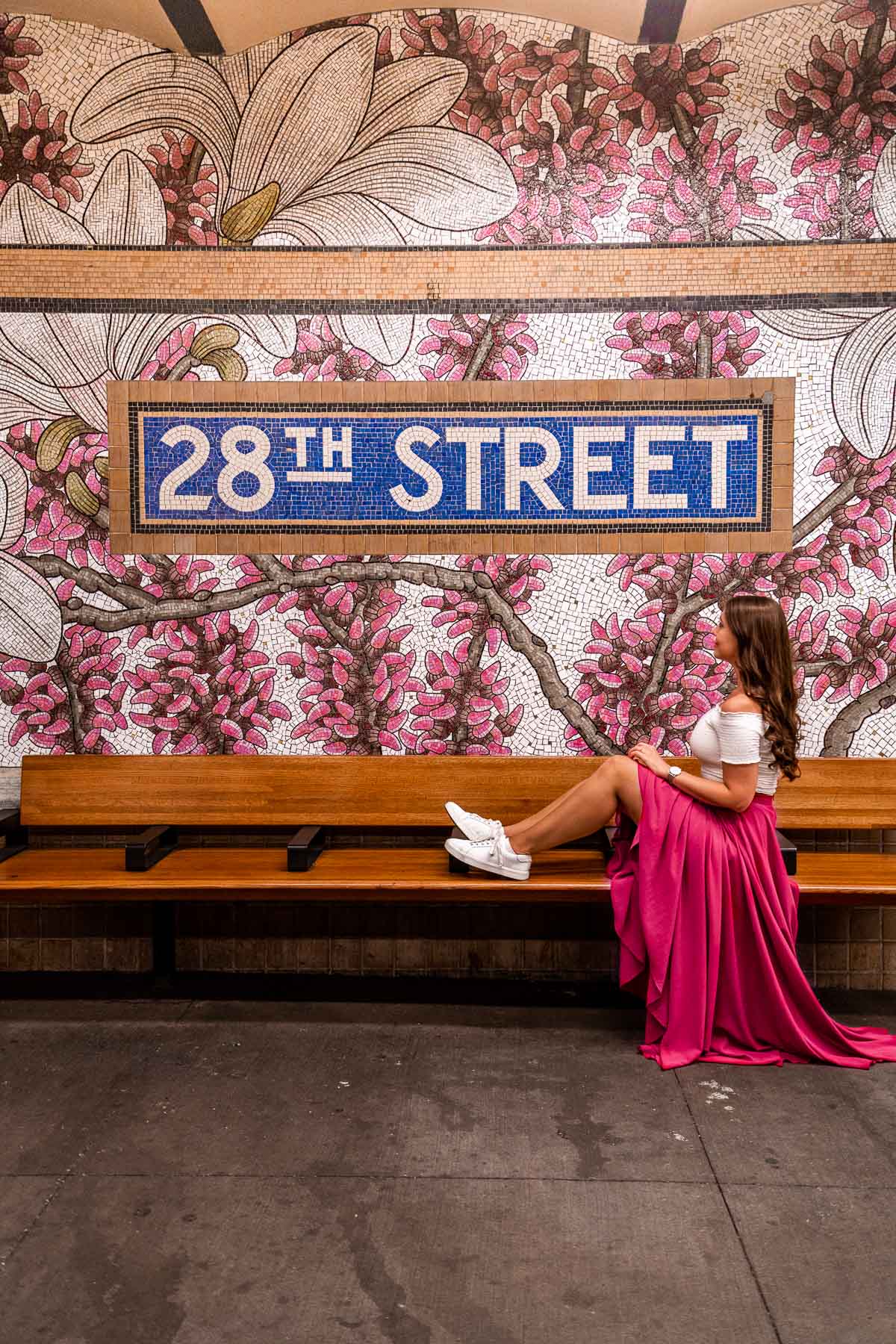 Girl in pink skirt sitting under a Flower mural at 28th Street Subway Station, New York