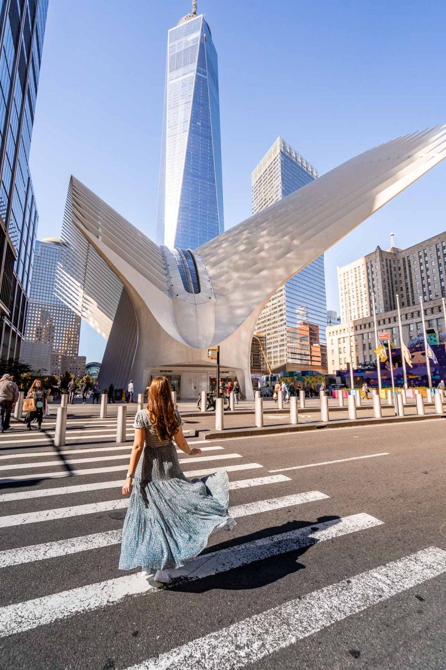 Girl in blue dress in front of the Oculus Center and One World Trade Center in New York
