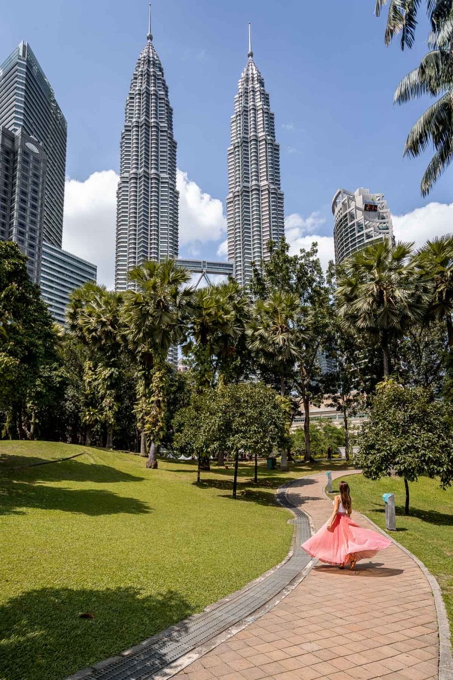 Girl in pink skirt in front of the Petronas Towers in Kuala Lumpur