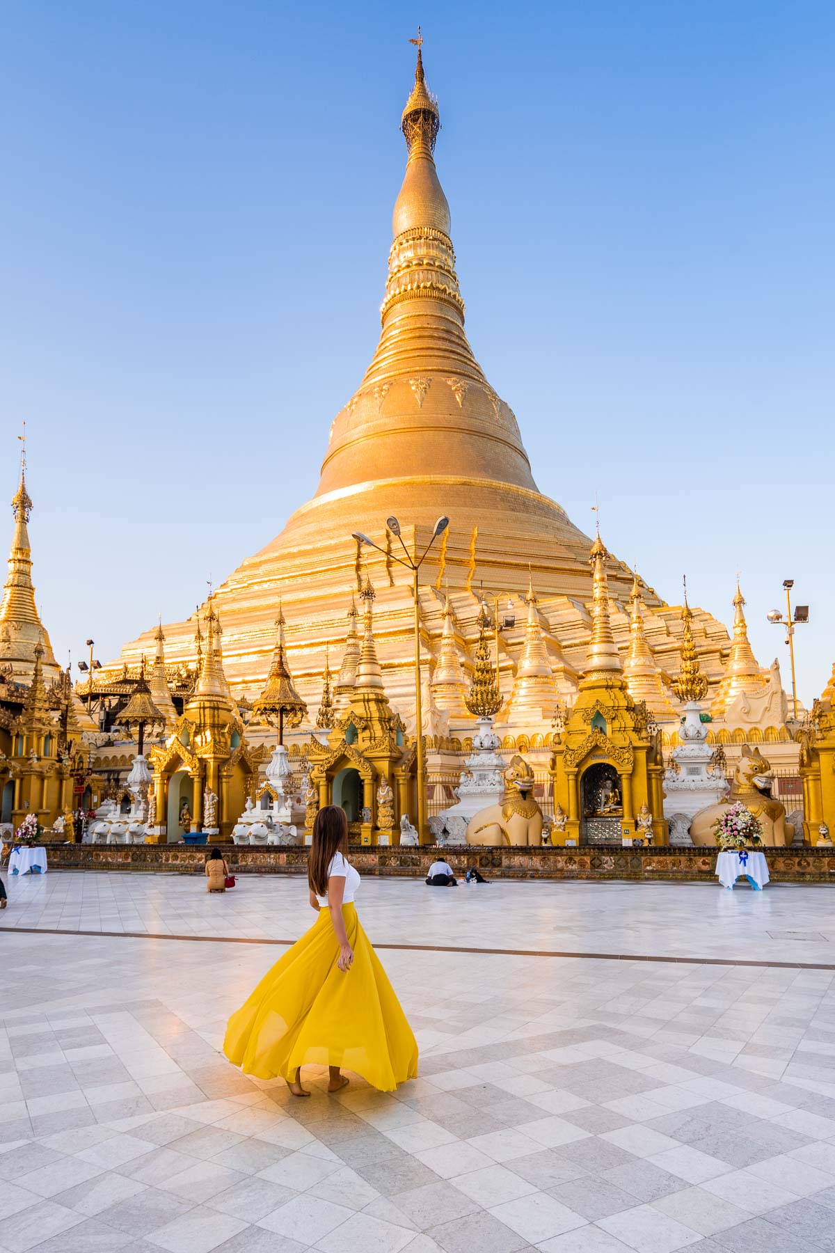 Girl in yellow skirt in front of the golden Shwedagon Pagoda in Yangon, Myanmar