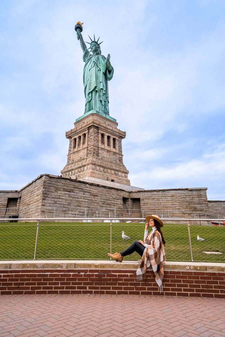 Girl sitting below the Statue of Liberty in New York