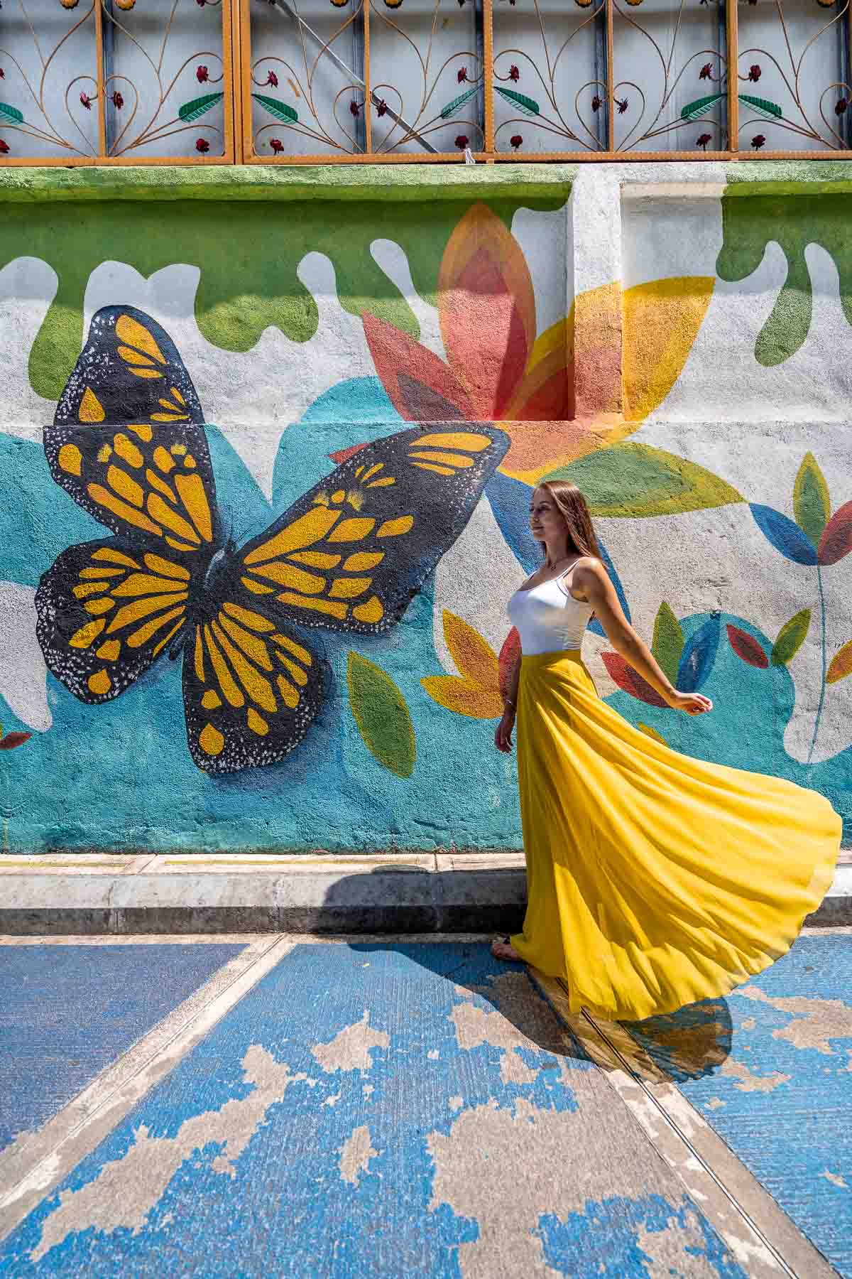 Girl in yellow skirt standing in front of a butterfly mural in Kuala Lumpur