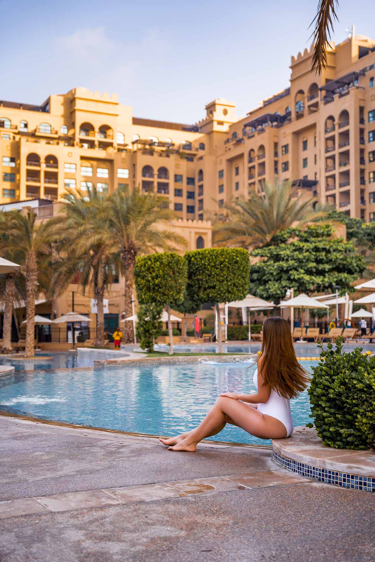 Girl in white swimsuit sitting at the Pool at Fairmont the Palm