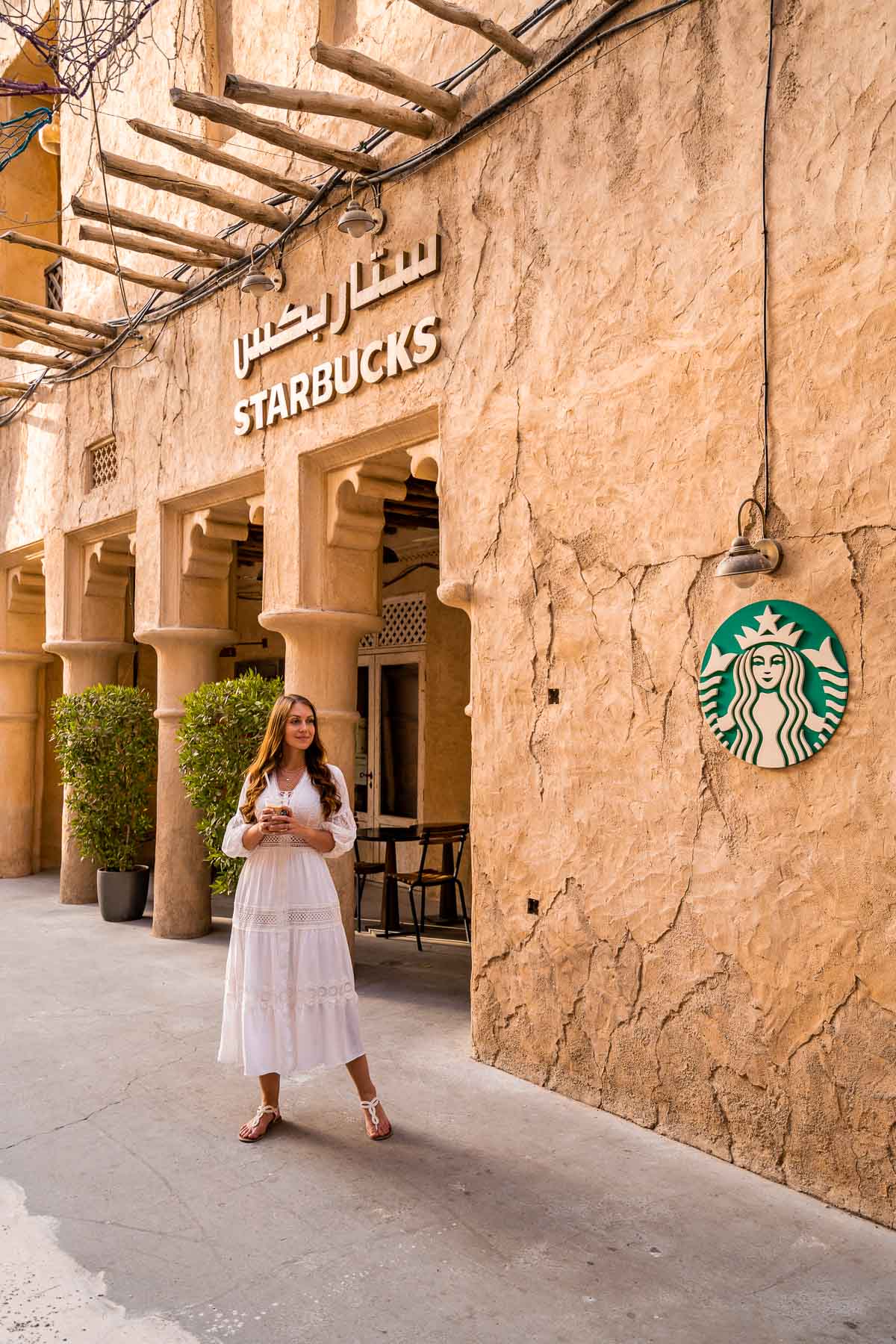Girl in white dress in front of a Starbucks on Al Seef Street in Dubai
