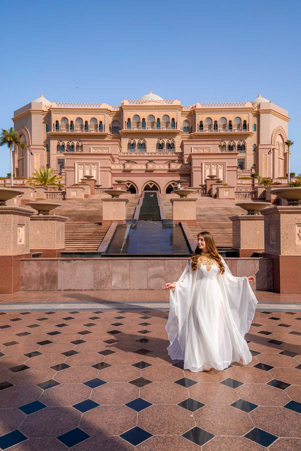 Girl in white abaya in front of Emirates Palace, one of the most Instagrammable places in Abu Dhabi