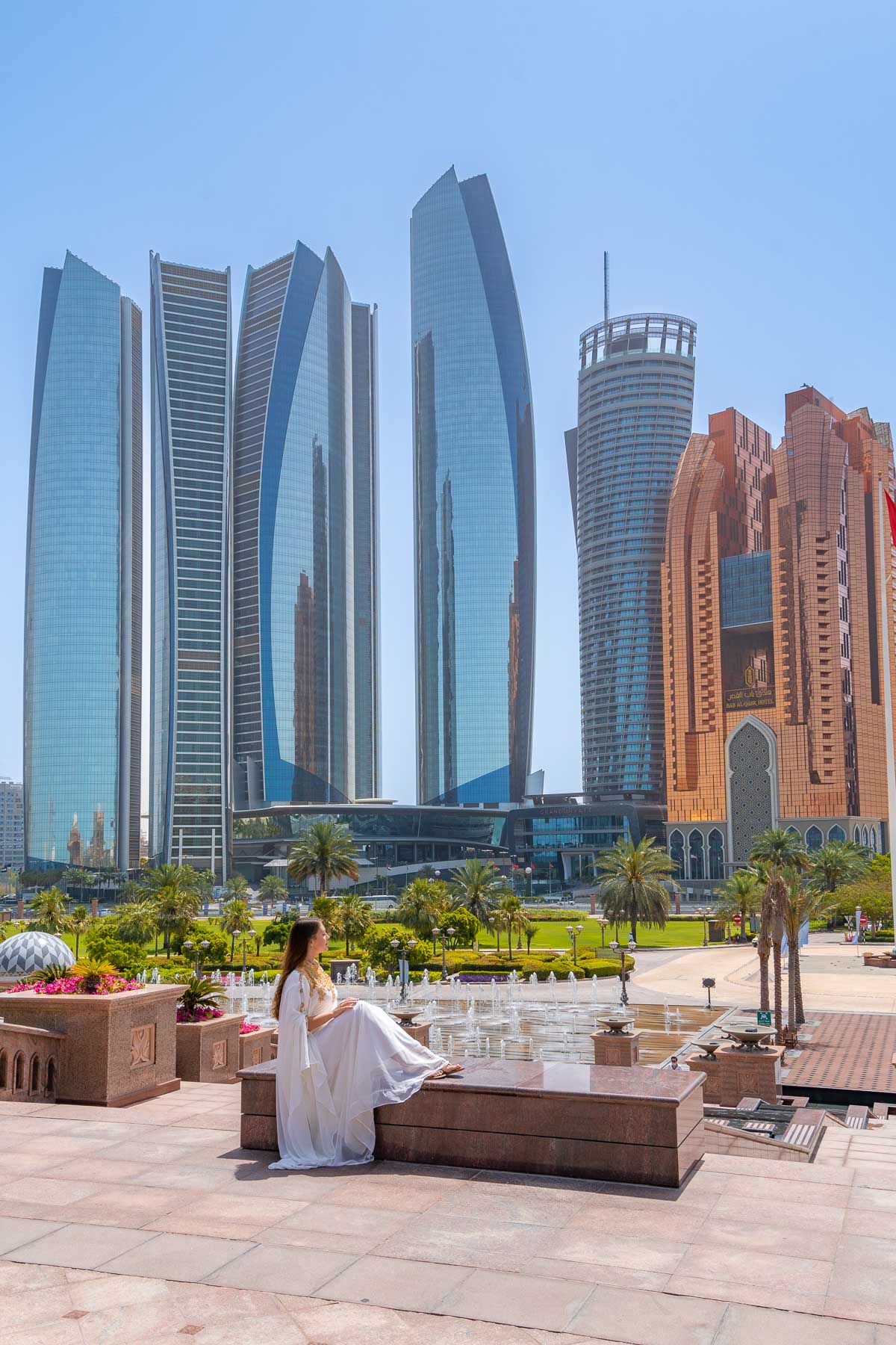 Girl in white abaya in front of the Etihad Towers in Abu Dhabi