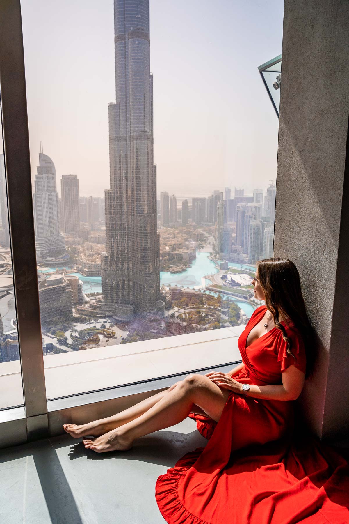 Girl in red dress in Sky Views Observatory overlooking the Burj Khalifa