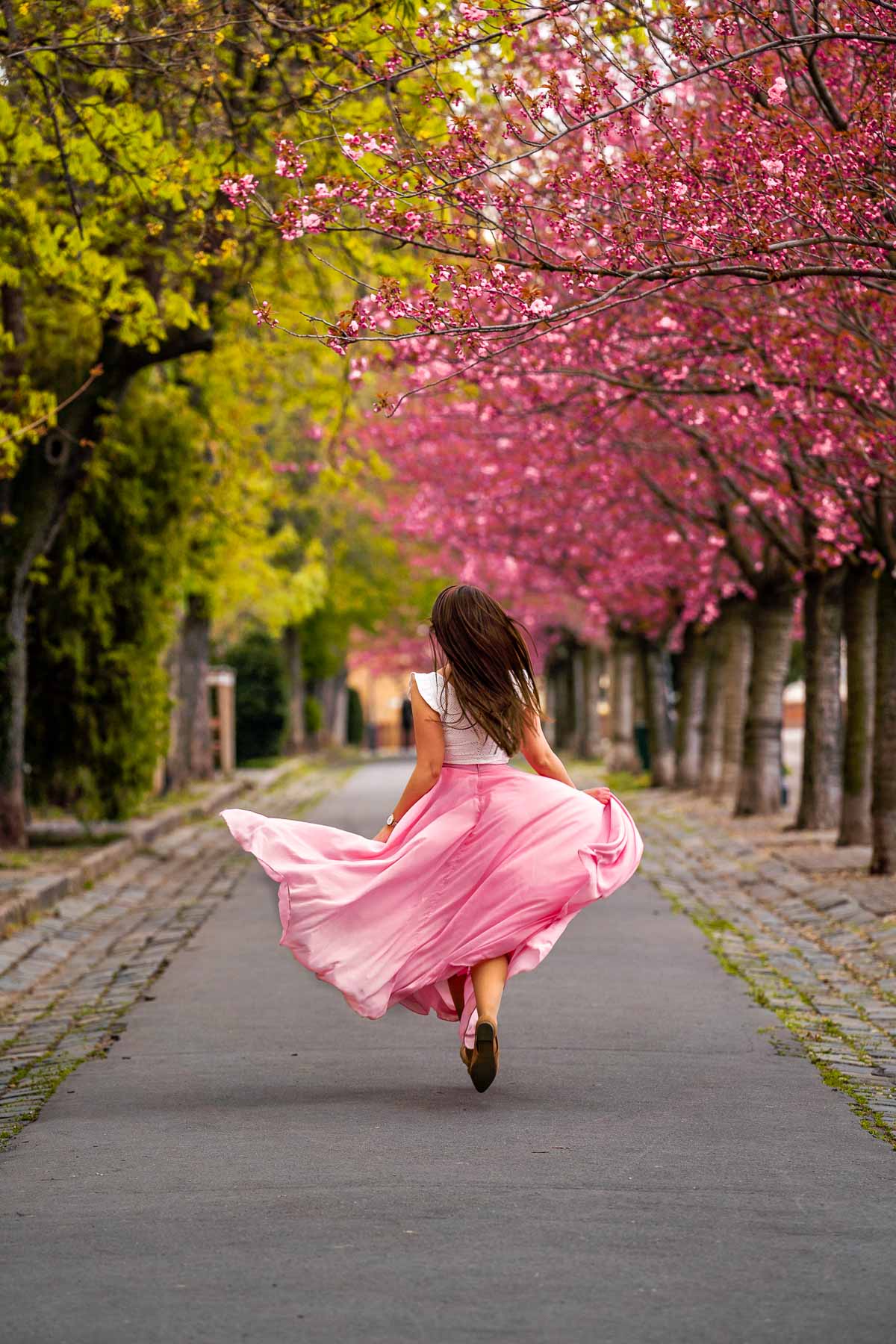 Girl running on Toth Arpad Promenade under the cherry blossoms