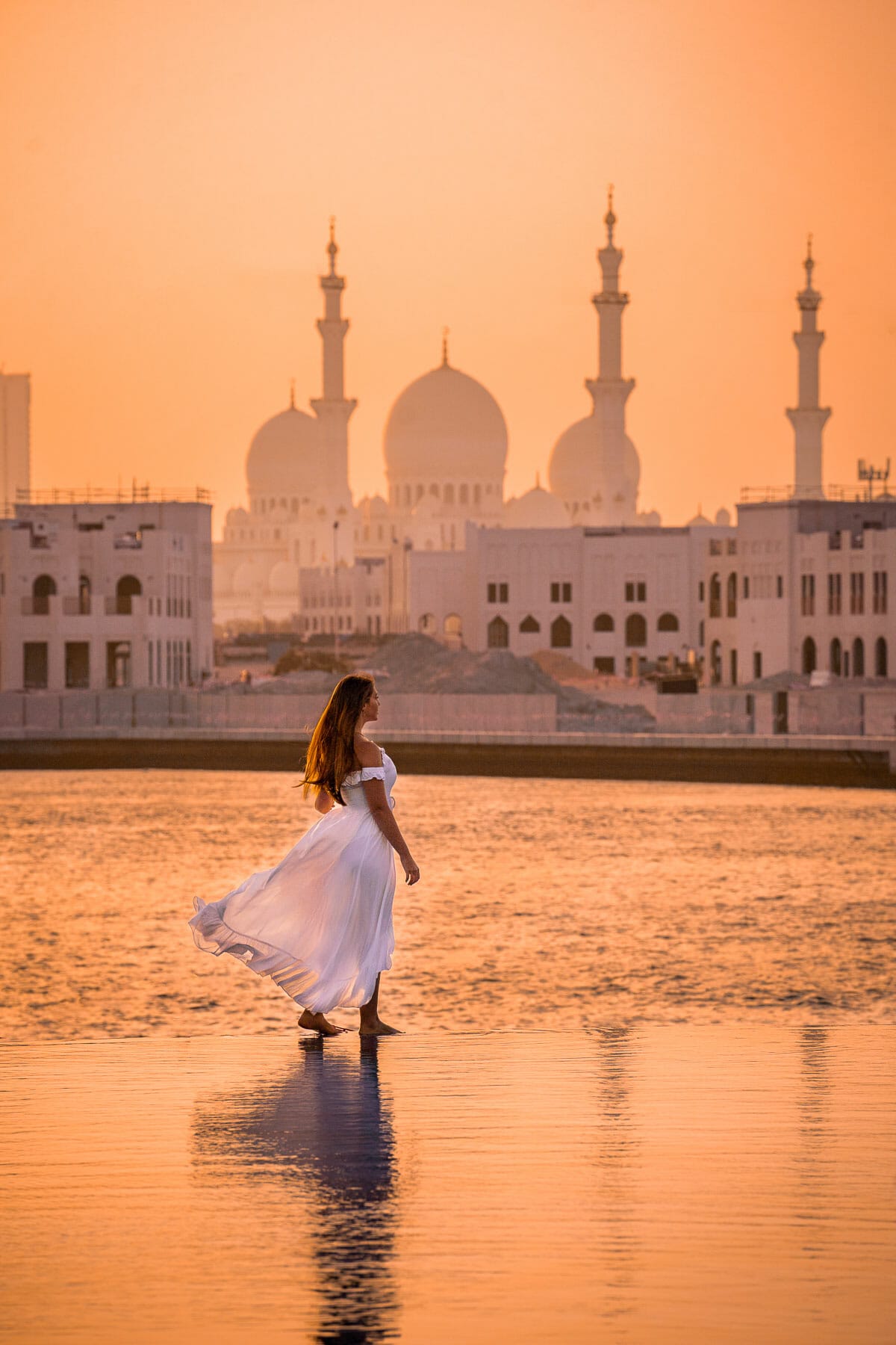 Girl walking on the edge of the pool at Shangri La Abu Dhabi overlooking the Grand Mosque at sunset
