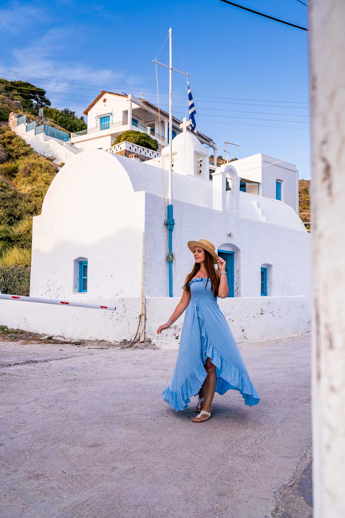 Girl in blue dress in front of a white church in Klima, Milos