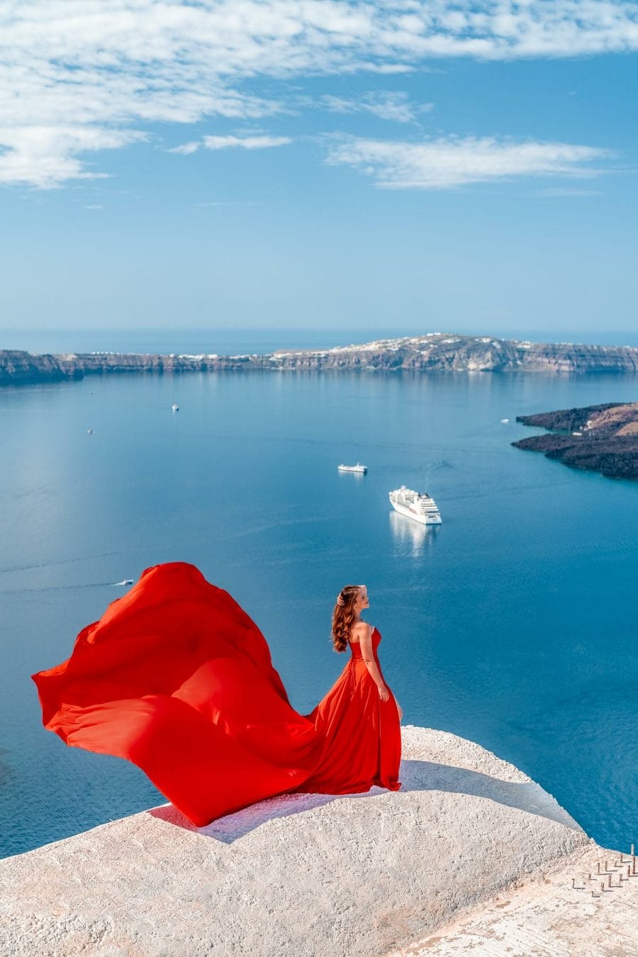 Girl in a red flying dress in Santorini