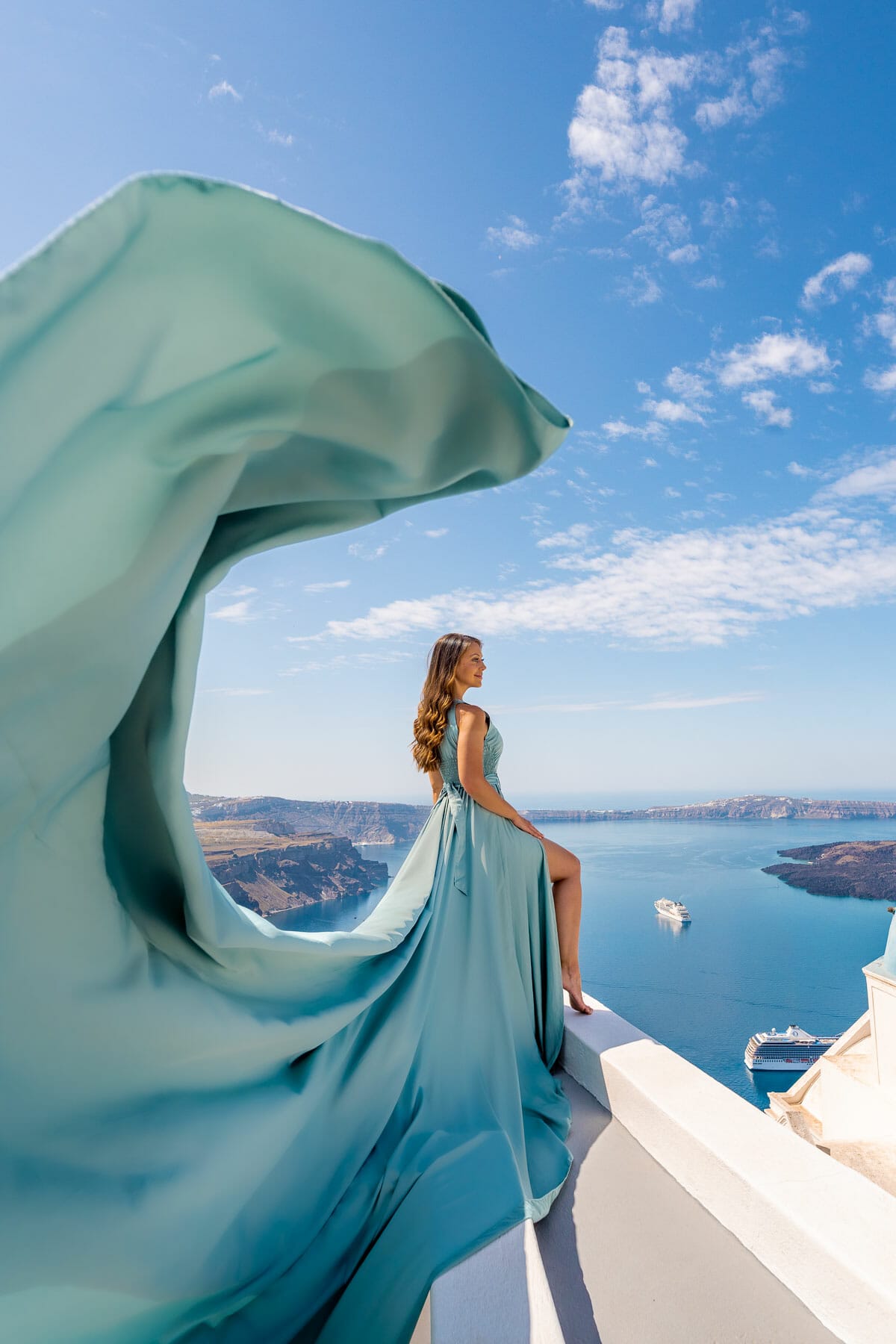 Girl in a blue flying dress in Santorini