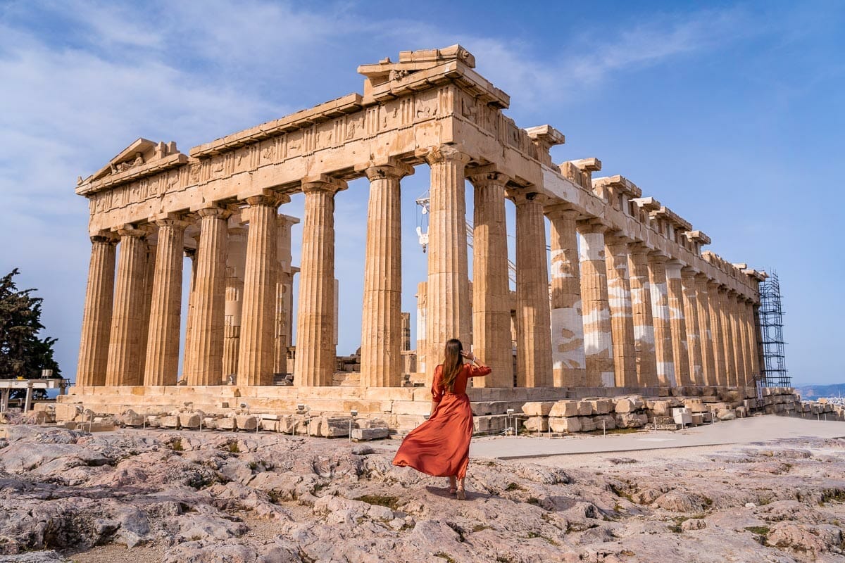Girl in orange dress in front of the Parthenon in Acropolis, Athens