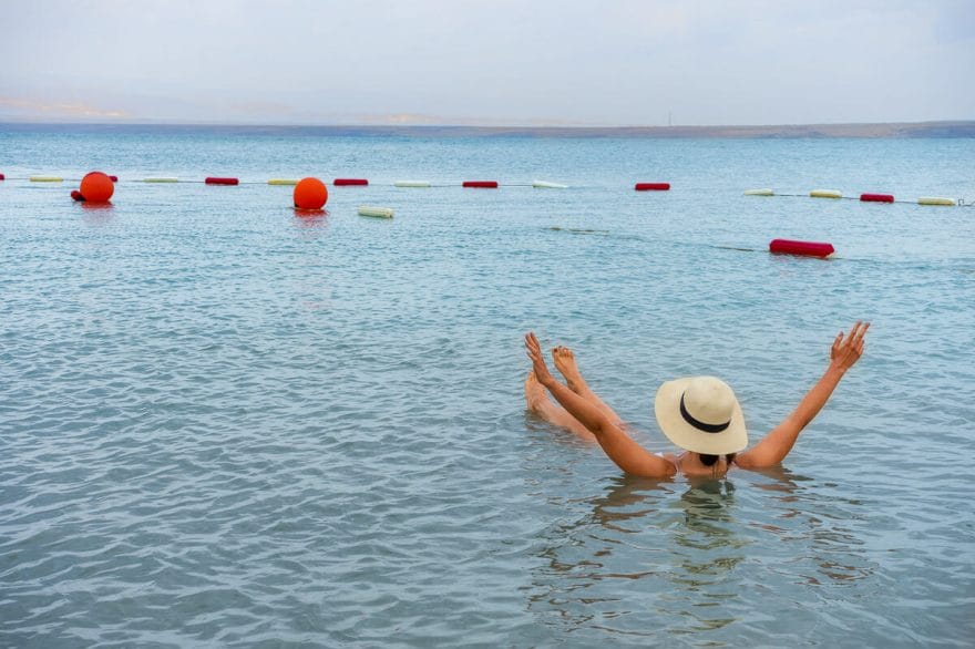 Girl in a straw hat floating in the Dead Sea in Jordan