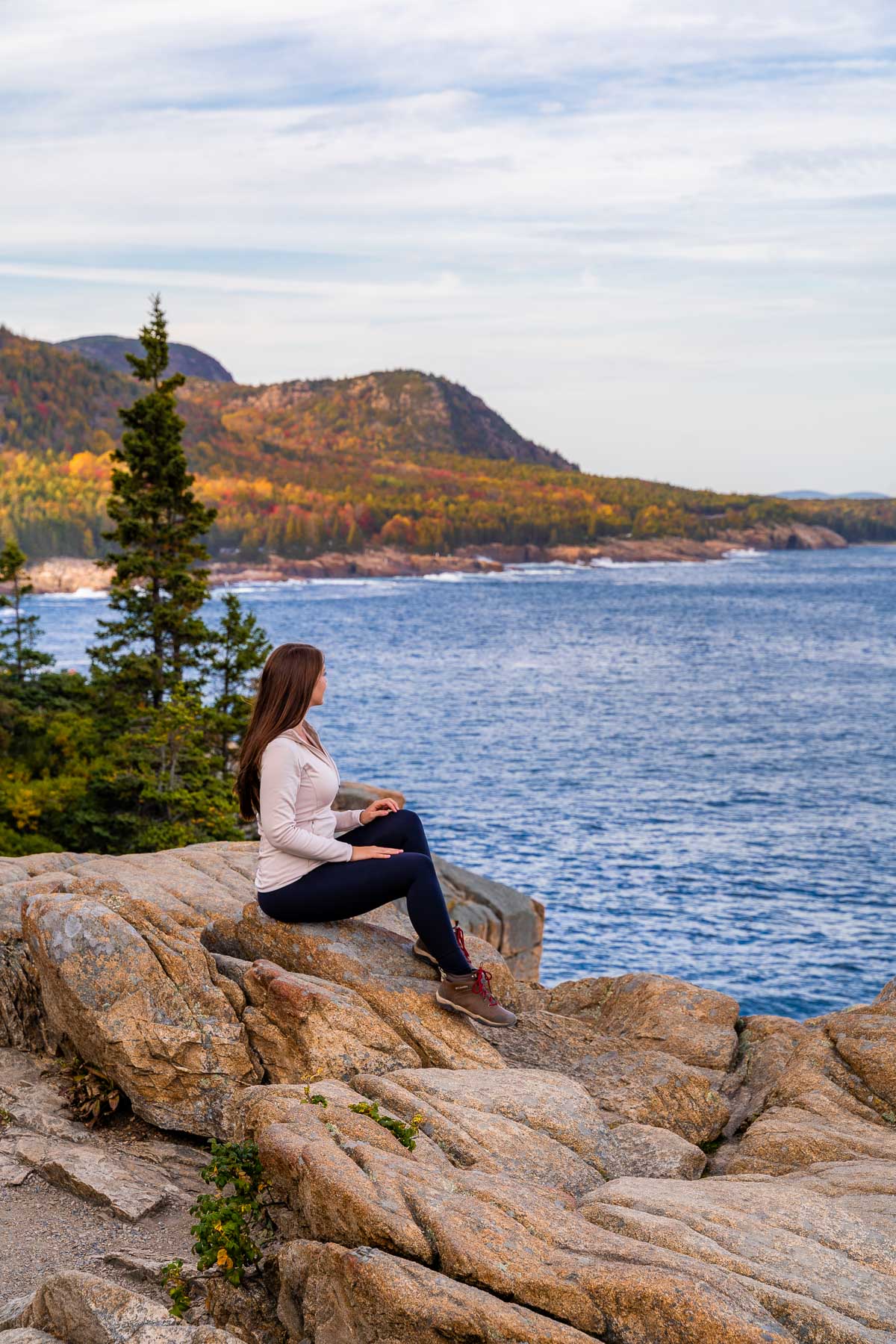 Girl sitting on a rock at Otter Cliff, Acadia National Park